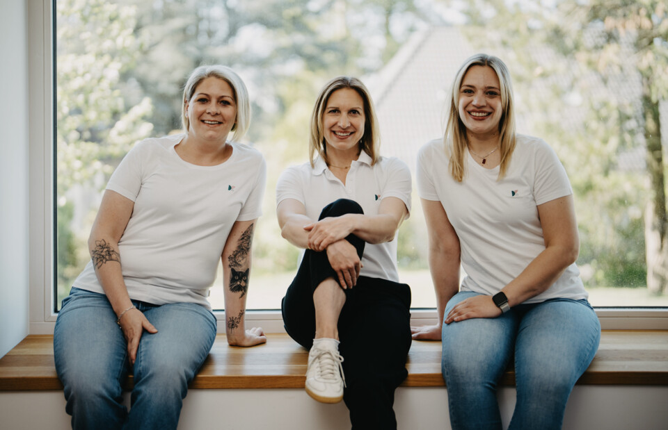 Von links nach rechts: Charlene Antes, Christina Berger und Jana Hellmann sitzen entspannt nebeneinander auf einer h&ouml;lzernen Fensterbank.